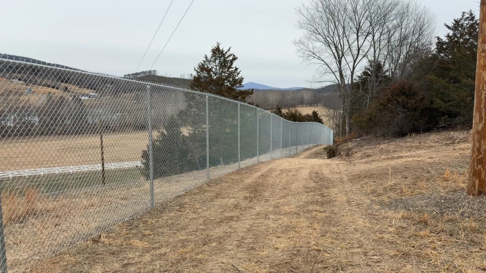 Fence line running downhill across pasture toward the mountains
