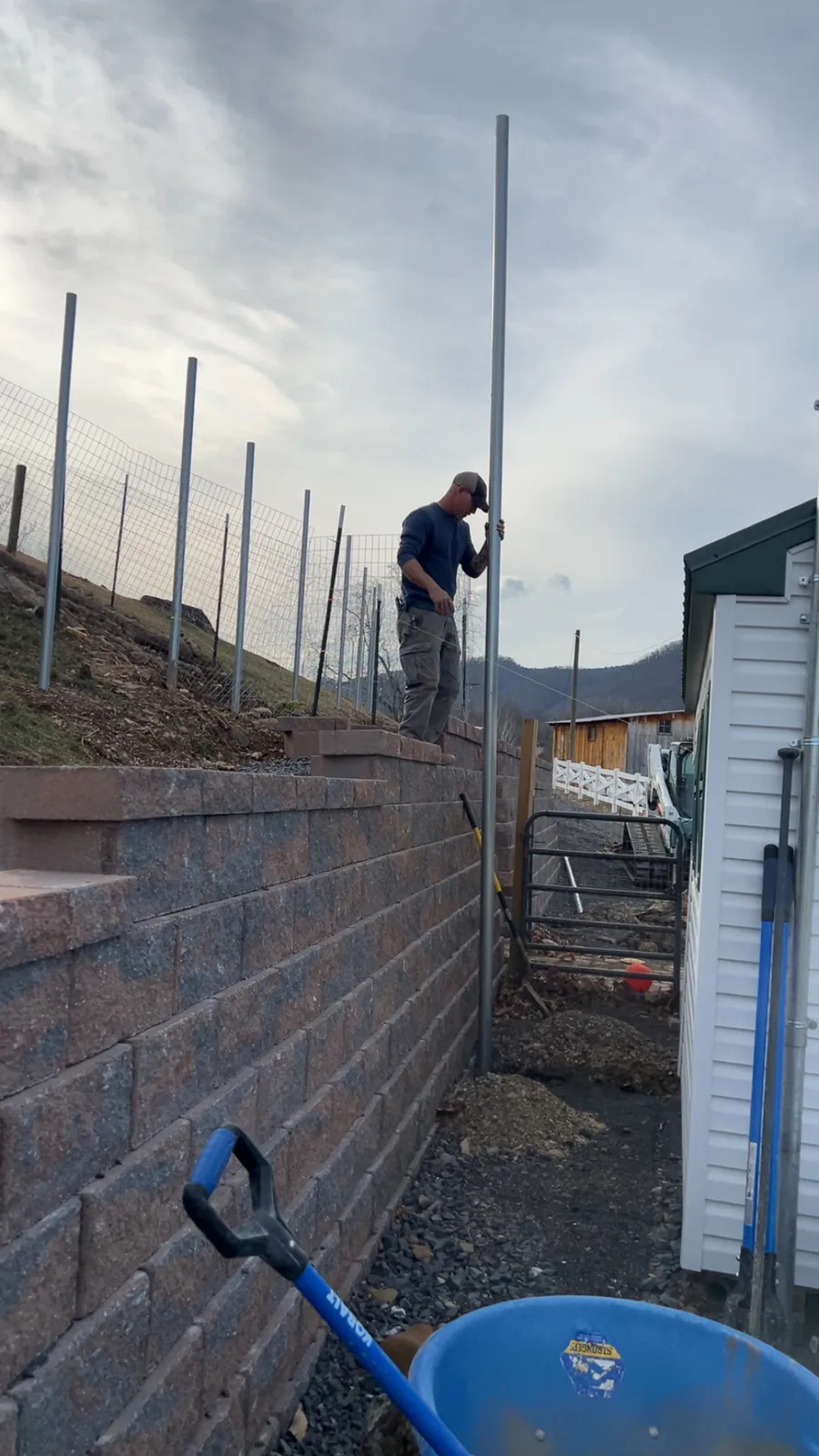 Setting fence posts above a block retaining wall on a farm property