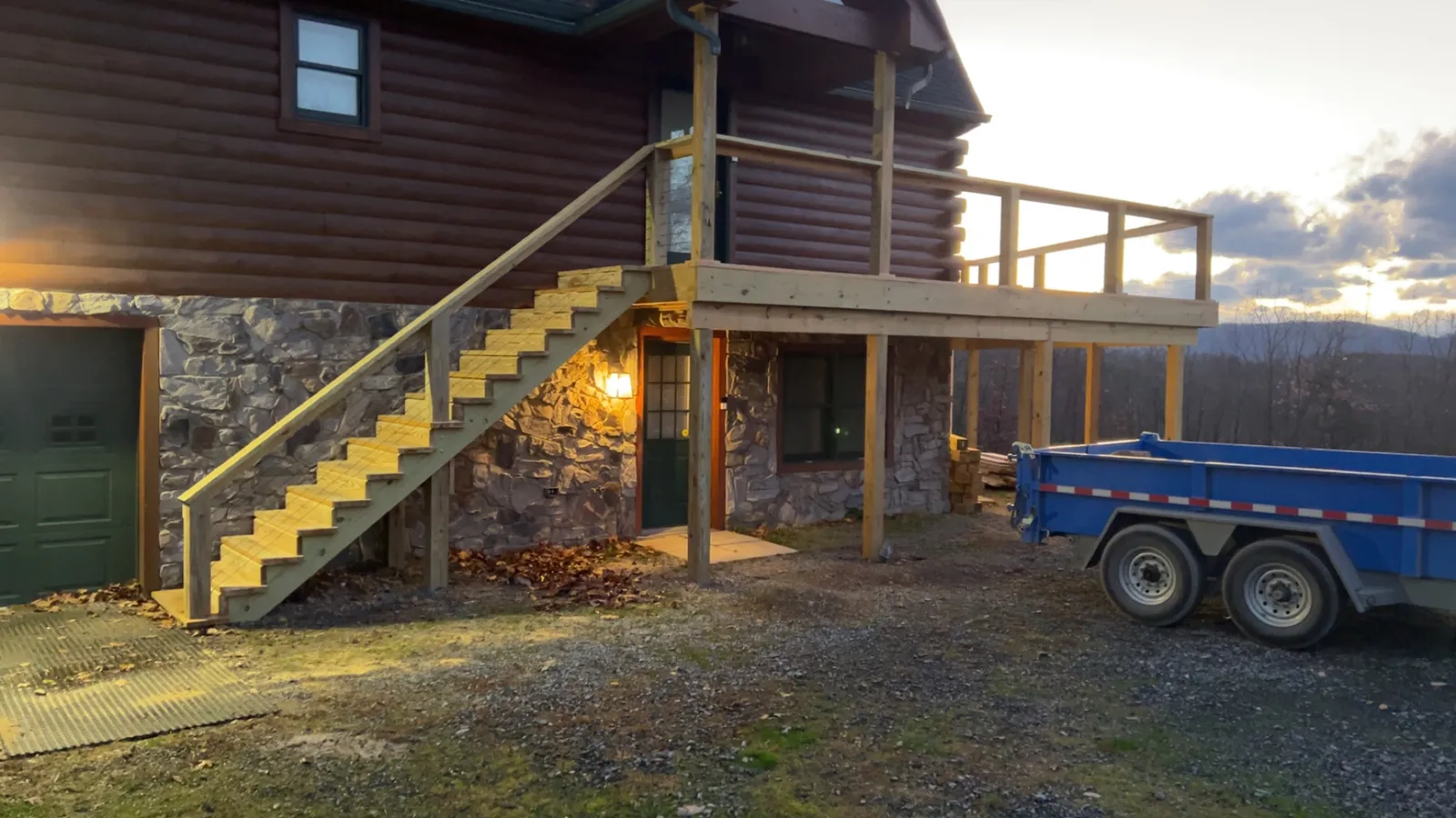 New porch stairs and framing going up on a stone-chimney lodge
