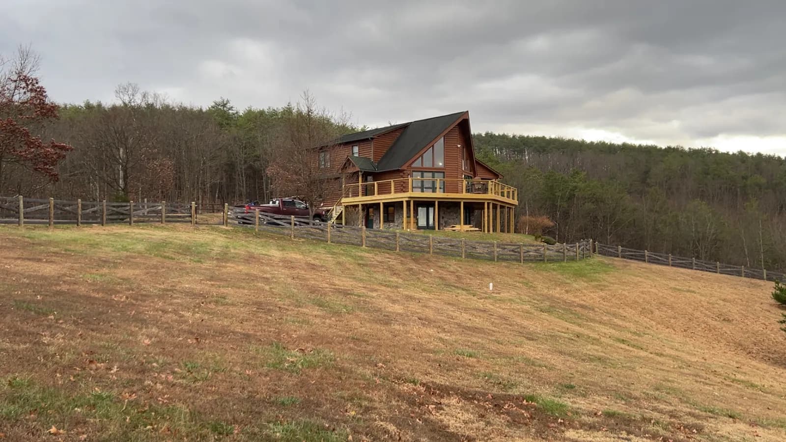 New wraparound deck on a log home with a split-rail fence line