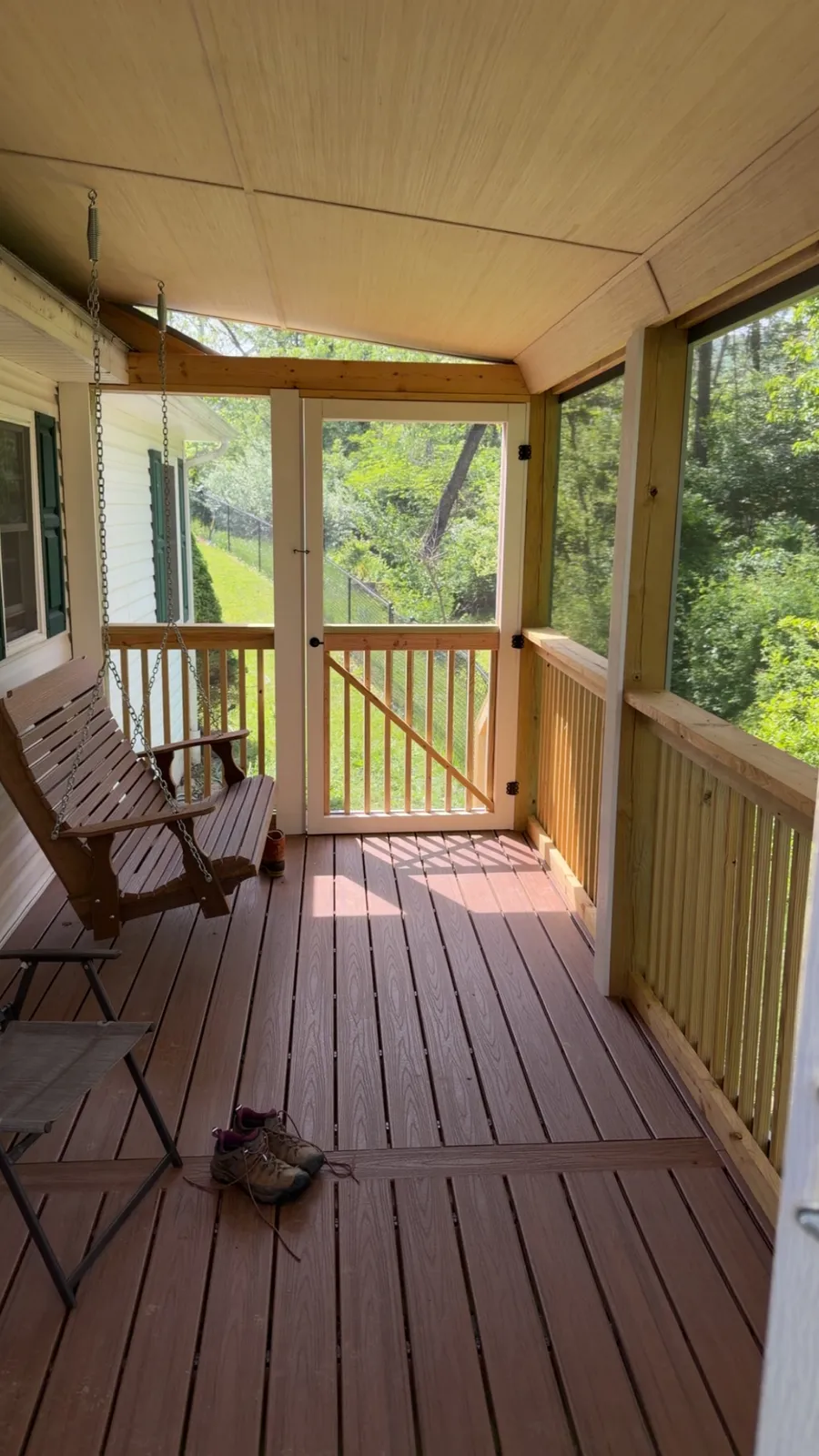 Screened porch with a hanging porch swing and composite decking