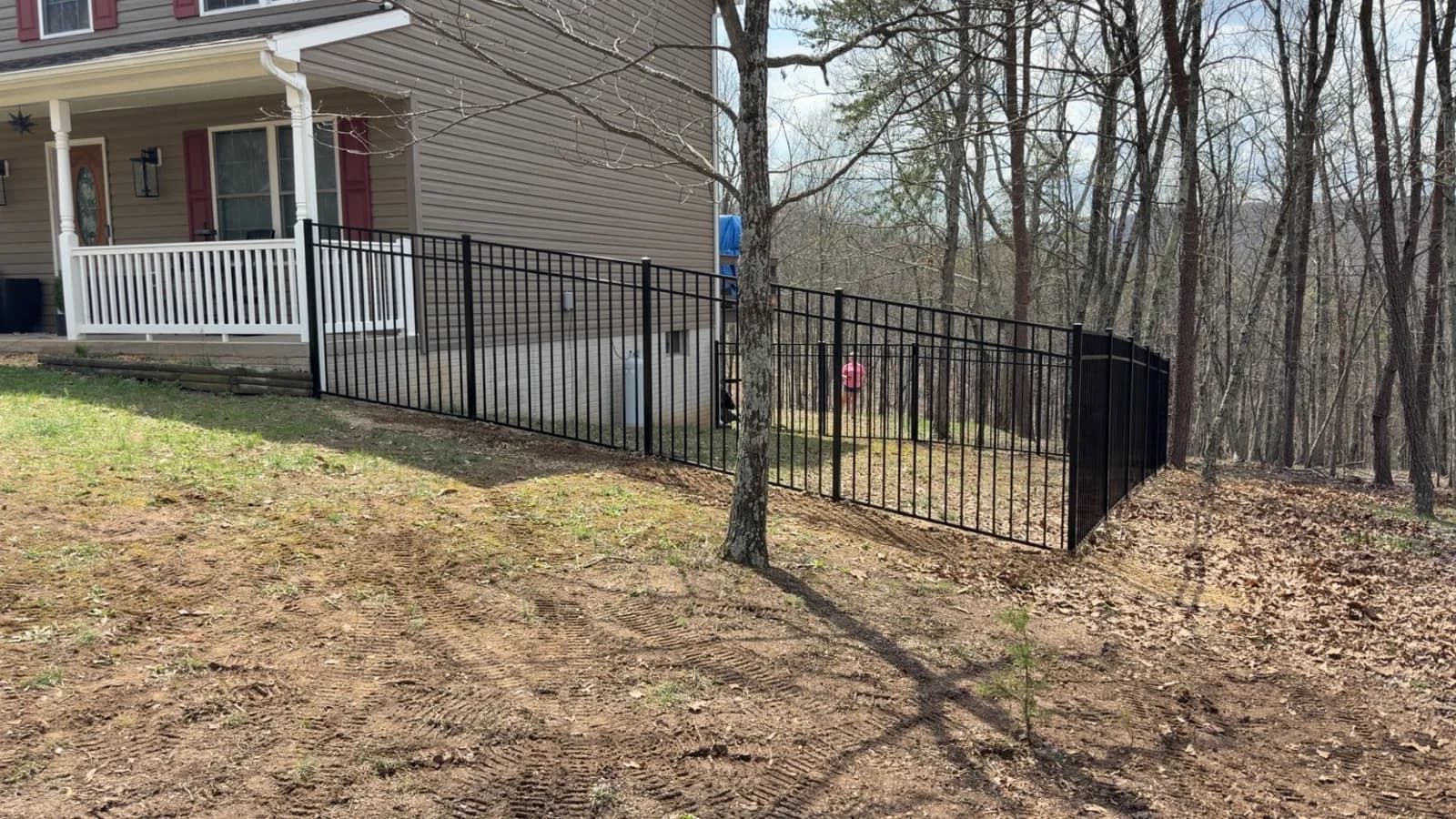 Black ornamental metal fencing with a covered porch behind