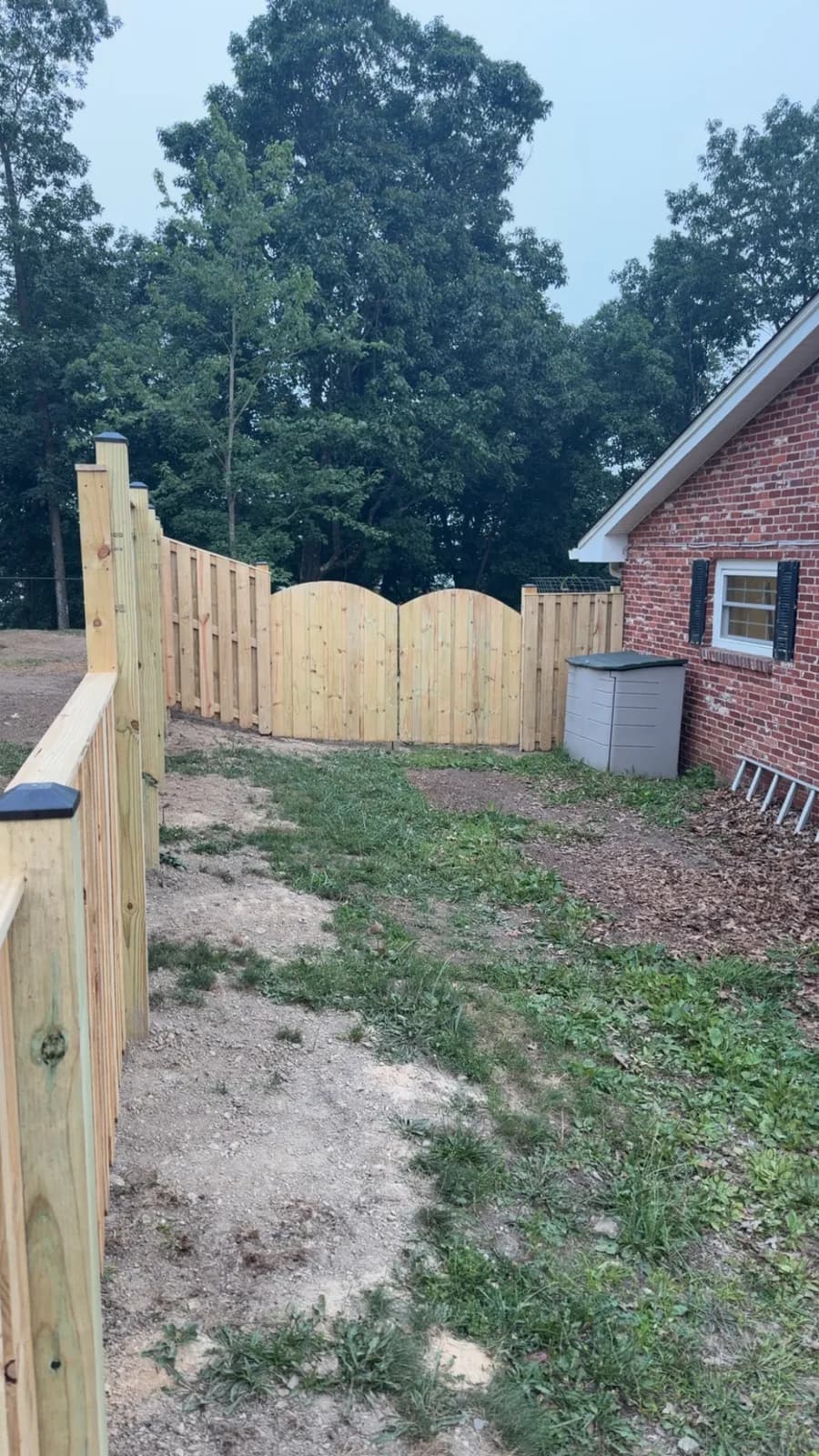 New wood shadowbox privacy fence with custom arched double gate at a brick home