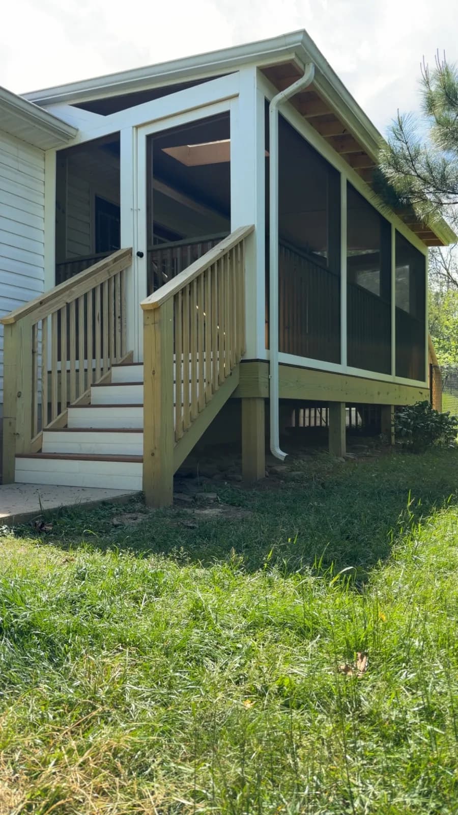Finished screened porch addition with new wood stairs and white-framed screen panels